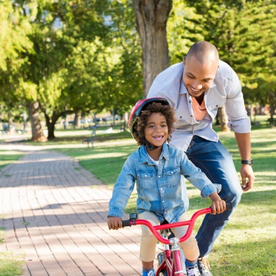 Dad teaching daughter to ride bike | Shutterstock, Rido