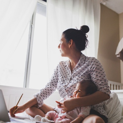 Latina mom with baby work at home | Getty Images