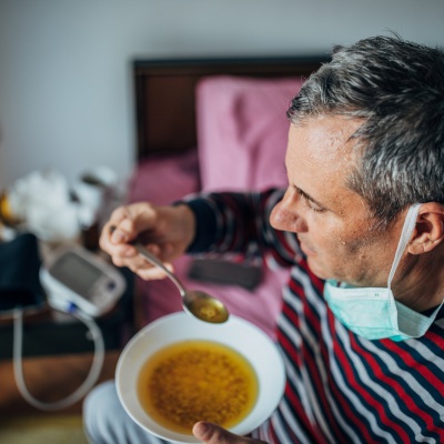 Sick man eating soup | Getty Images