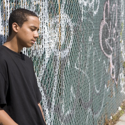 Young man leaning against fence