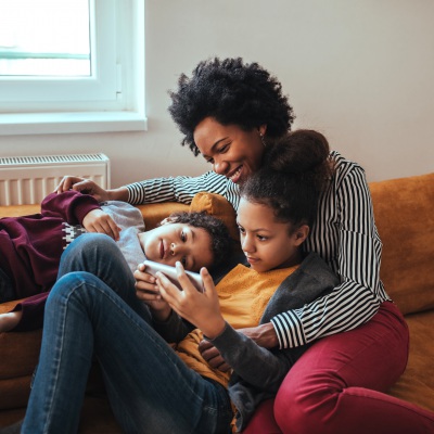 Mother and two children on couch happy | Getty Images