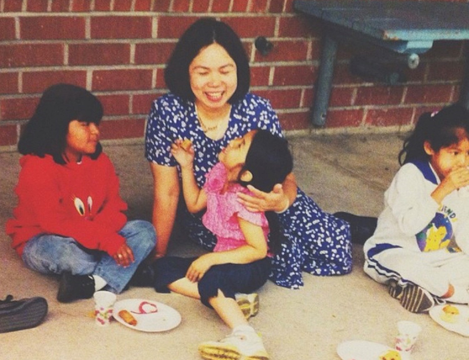 Mother and daughter sitting on the side of a building smiling